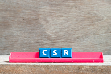 Tile letter on red rack in word CSR (Abbreviation of corporate social responsibility) on wood background