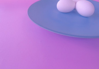 A light blue neutral plate with white chicken eggs on a neutral pink background. Free space to write.