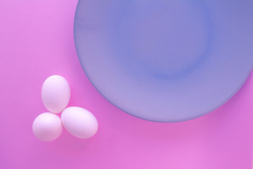 A light blue neutral plate with white chicken eggs on a neutral pink background. Free space to write.
