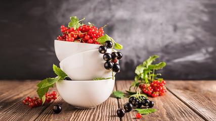 Fresh ripe red black currant berry in white bowls stand in a pile on the table. Selective focus. Horizontal frame.
