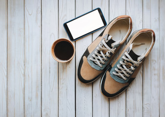 Stylish suede new sneakers stand on a wooden gray background with hot coffee. Sport, morning,...