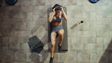 Top View of Professional Female Bodybuilder Doing Bicycle Crunches while Lying on the Yoga Mat in the Hardcore Gym. Muscular and Athletic Beautiful Woman Muscle, Power and Cardio Workout. Zoom Out - Powered by Adobe