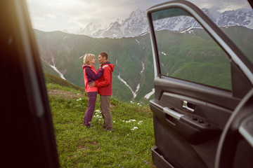 Happy couple hugs on beautiful nature and mountains out of car 