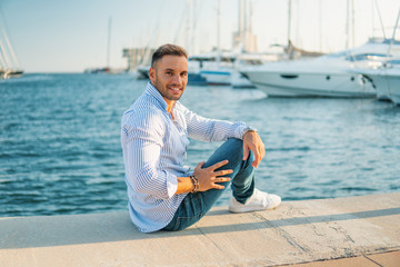 Fototapeta na wymiar Young rich man at Yacht Club. Businessman is smiling and Relaxing in the gulf with seaview and luxury ships