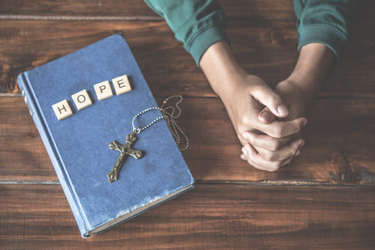 Christian hands are praying and praying to God. With a Bible book placed on the side And have the letter "HOPE"