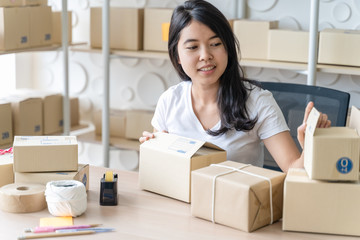 Fototapeta na wymiar Asian freelance woman working at home and start up small business entrepreneur SME with internet online. woman is preparing the goods in the package box to prepare the delivery for the customer.