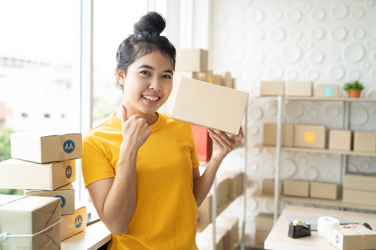 Portrait of Asian freelance woman working at home and start up small business entrepreneur SME with internet online. Young woman is showing hand of like sign.