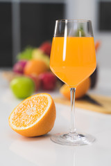 One glass of orange juice and a slice of orange on a white table in the kitchen