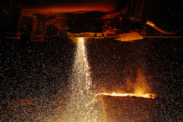 A stream of hot metal pours into the ladle. Electric arc furnace shop EAF. Metallurgy.