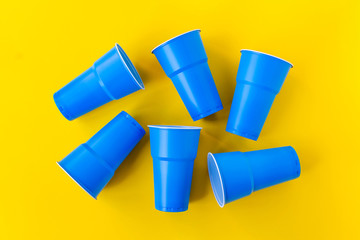Vibrant blue plastic cups upside down on yellow background. Closed composition image. Top view. No plastic and eco concept.