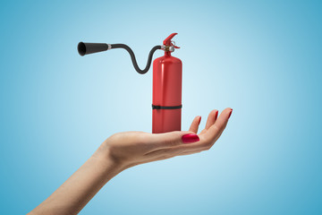 Female hand holding red foam fire extinguisher on blue background