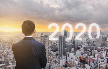 Businessman looking at city sunrise with 2020 new year in the city