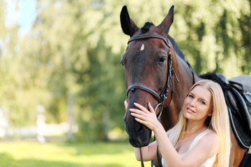 Obraz premium Young attractive blond woman hugs a brown horse.