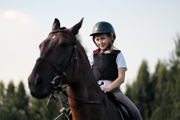 Obraz premium Girl teenager jockey sits on a brown horse in nature.