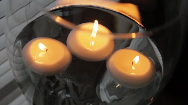 Two water filled wine glasses of white lit floating candles.
