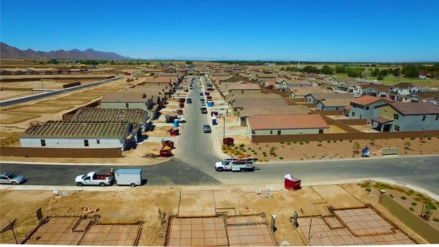 Aerial shot of a work truck driving through as the camera pans down to the cement foundation of new home sites