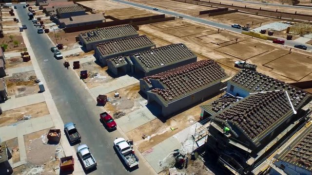 Aerial shot of new homes under construction. With new ceramic tiles bundles on the roof. New roof installation