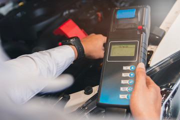 Man inspection holding Battery Capacity Tester Voltmeter.for service maintenance of industrial to engine repair.In Factory transport automobile automotive image