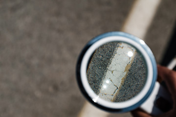 White diagonal line in the asphalt close up seen by a white loupe magnification