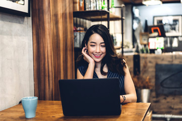 Businesswoman sitting and working with laptop computer and drink coffee at table in cafe