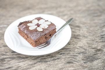 Chocolate cake, brownie fudge on white plate with wooden background