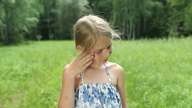 Smiling cute girl touches her face with her hand and smiling turning. Childhood. Kids, nature, summer casual fashion, beauty.