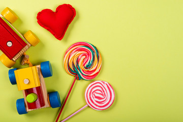 Children's Day. Wooden train, lollipop and heart made of fabric on neon green background. Copy space.