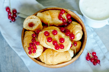Croissants with currant berries on a wooden tray. The concept of a wholesome breakfast.