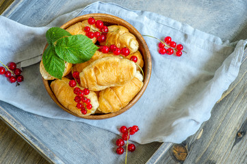 Croissants with currant berries on a wooden tray. The concept of a wholesome breakfast.