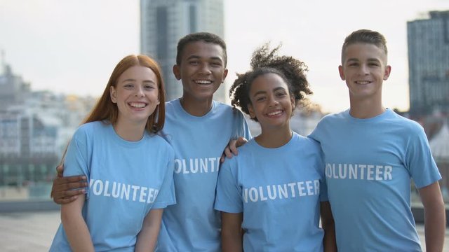 Smiling young people volunteer t-shirts looking camera, social teamwork, help