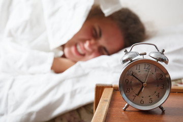 Young sleeping woman and alarm clock