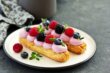 Homemade eclair with berry cream and fruits. . Pastry.
