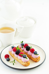 Homemade eclair with berry cream and fruits. . Pastry.
