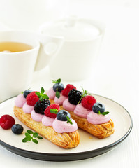 Homemade eclair with berry cream and fruits. . Pastry.