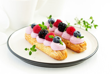 Homemade eclair with berry cream and fruits. . Pastry.