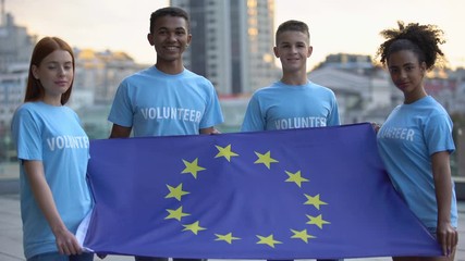 Young multi-racial volunteers holding European Union flag, international unity - Powered by Adobe