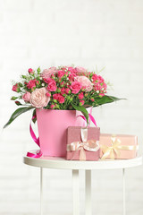 Beautiful bouquet of flowers and gift boxes on table against light background