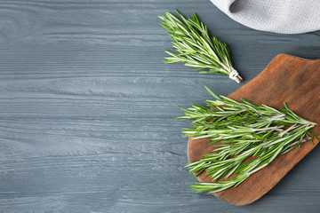 Fresh green rosemary on blue wooden background, flat lay. Space for text