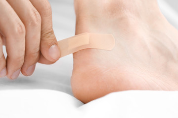 Man applying adhesive bandage on heel indoors, closeup