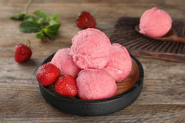 Plate with delicious strawberry ice cream on wooden table, closeup