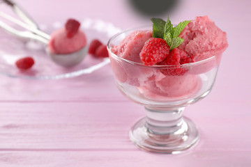 Delicious raspberry ice cream in dessert bowl on pink wooden table, closeup. Space for text