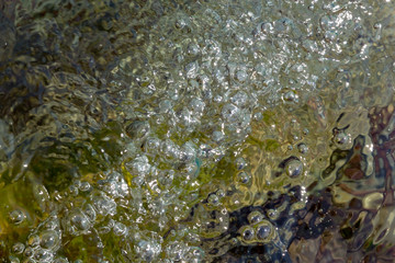 Background of greenish transparent water with air bubbles on the surface.