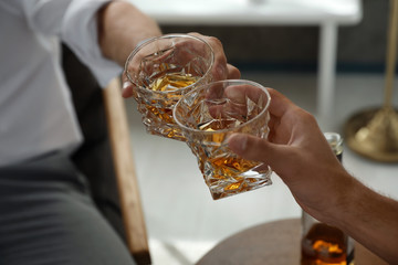 Young men drinking whiskey together at home, closeup
