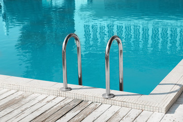 Modern swimming pool with ladder at resort