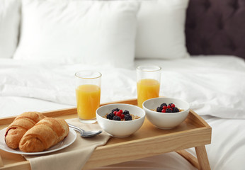 Fototapeta na wymiar Tray with tasty breakfast on white bed