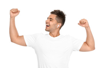 Happy young man listening to music through wireless earphones on white background