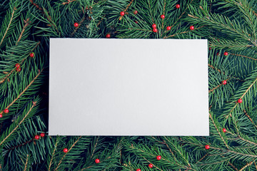 Blank card on Christmas tree branches as background, top view. Space for text