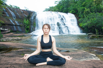 Fototapeta na wymiar Young asain women practicing yoga at front of grand waterfall.