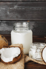 Broken coconut and coconut milk on black wooden background