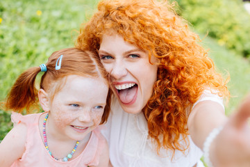 Joyful red haired mother posing on camera